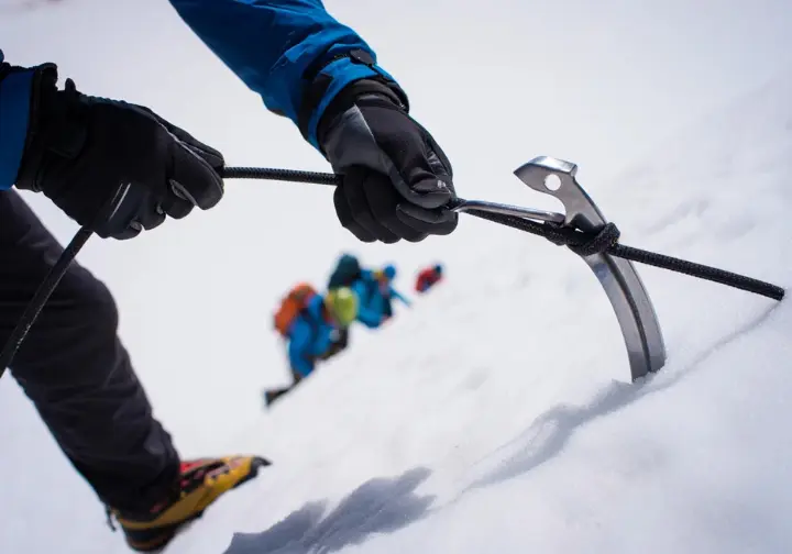 Close-up of a mountaineer's hands adjusting climbing gear on a snowy slope, representing skills, training, and acclimatization for mastering Andean ascents in Peru.