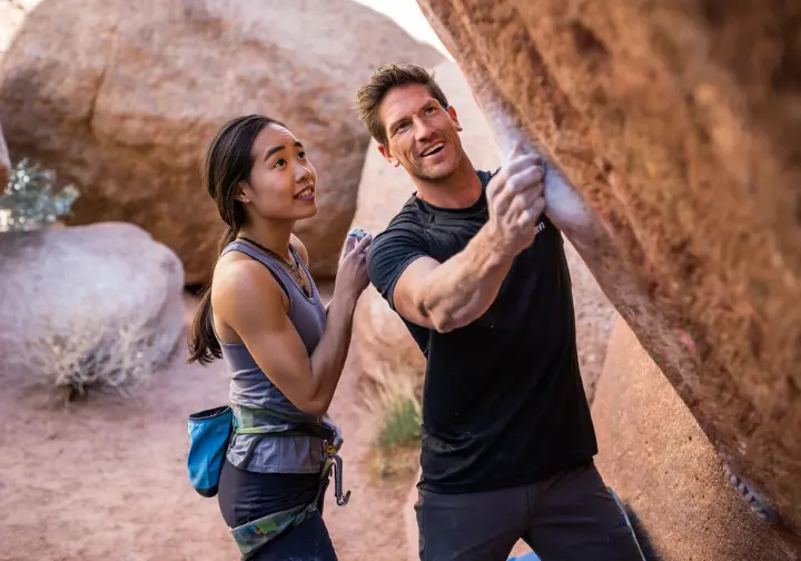 Two diverse climbers discussing strategy at a Red Rocks boulder, symbolizing the sharing of insider bouldering tips for all levels from V0 to V-Hard.