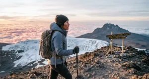 Climbing Kilimanjaro? Days Beat Fitness Every Time Trekker nearing Uhuru Peak at dawn while climbing Kilimanjaro above the clouds