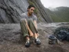 Why 98% of Climbers Buy Climbing Shoes Too Tight Climber sitting on a crag boulder easing on a Butora Endeavor climbing shoe before a route
