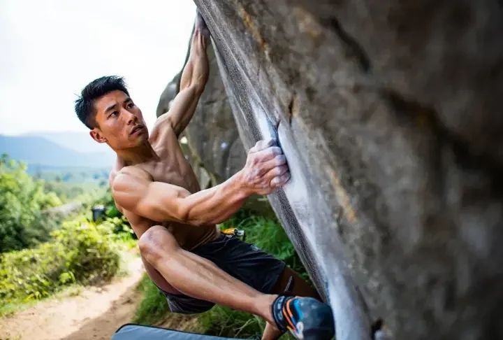 Climber tackling a short, no-rope outdoor boulder problem, showcasing the essence of bouldering and what a boulder problem entails.