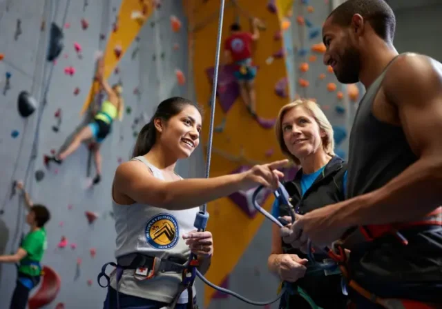 Instructor guiding students on CWI certification choices (AMGA, CWA, PCIA) for climbing wall instructor certification.
