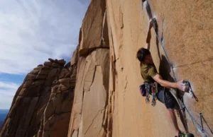 Understanding Trad Climbing: Beyond Placing Protection Climber placing protection on a vast cliff, illustrating the depth of understanding trad climbing beyond just the gear, a key aspect of what is trad climbing.