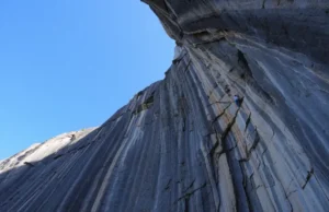 Unveiled: World’s Hardest Climbing Route Right Now A massive, sunlit limestone cliff, showcasing the world's hardest climbing route under a clear blue sky, conveying extreme difficulty and challenge.