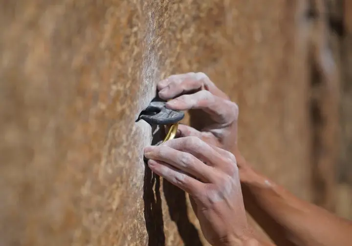 Close-up of a climber's hands placing trad gear into a rock crack, fundamentally defining what is trad climbing.