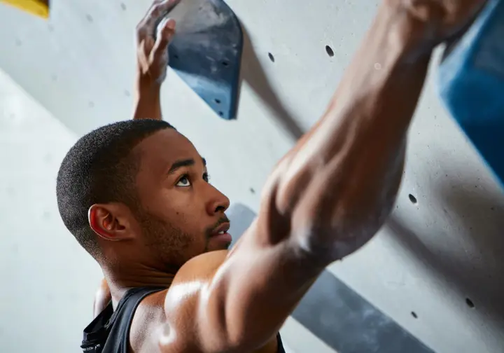 Male climber performing targeted finger strength training on a hangboard, essential for building bouldering strength and getting better at bouldering.