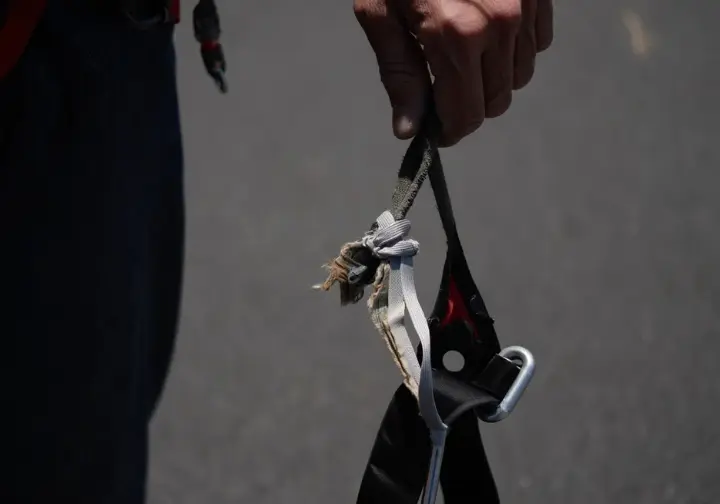 Close-up of critical damage on a climbing harness, such as a torn belay loop, illustrating a clear decision point for retiring it and impacting how long a harness lasts.