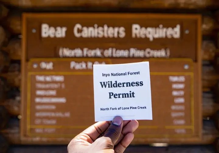 Navigating Mount Whitney Mountaineer's Route permits and regulations: hand holding an Inyo National Forest Wilderness Permit.