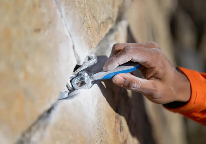 Climber's hand carefully removing trad gear, showcasing the ethics of clean climbing and environmental stewardship in what is trad climbing.