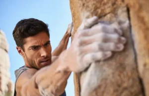 Master Grip Strength for Climbing: Exercises & Plans Climber mastering grip strength with chalked hands on a sunlit rock hold, showcasing exercises and plans for climbing.