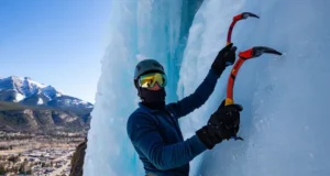 Master Ouray Ice Climbing: Park, Routes & Conditions Mastering Ouray ice climbing: climber on a spectacular ice route in the Ouray Ice Park, with the town and San Juan Mountains in view, detailing park, routes, and conditions.
