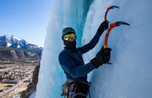 Master Ouray Ice Climbing: Park, Routes & Conditions Mastering Ouray ice climbing: climber on a spectacular ice route in the Ouray Ice Park, with the town and San Juan Mountains in view, detailing park, routes, and conditions.