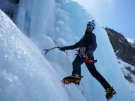 Mastering training for ice climbing: climber showcasing strength and endurance by swinging an ice tool into a steep blue ice formation.