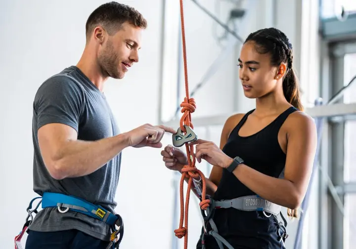 Safety first in learning how to rock climb: instructor and student performing a partner check to understand and mitigate risks.