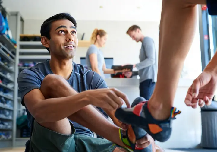 Getting started with your first steps into climbing: person trying on rental shoes to learn how to rock climb.