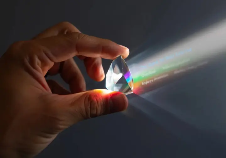 The big reveal for the best rock climbing exercise: a hand holding a prism refracting light into training principles like specificity and overload.