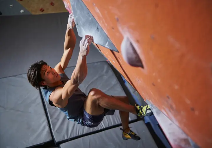 Bouldering safety and injury prevention tips for beginners: climber demonstrating a safe falling technique onto a crash pad.