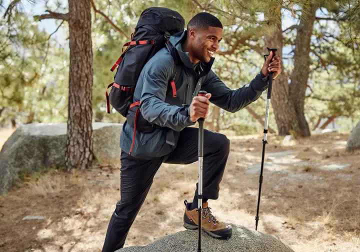 Forging mountain strength for mountaineering: diverse male mountaineer doing weighted step-ups with a backpack, focusing on power, stability, and load carrying in his physical training.