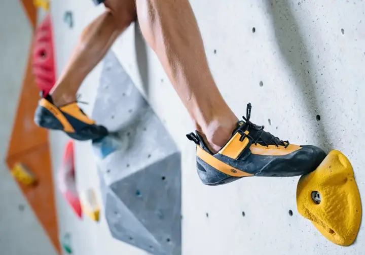 Mastering the moves to learn how to rock climb: close-up of feet using fundamental climbing techniques.