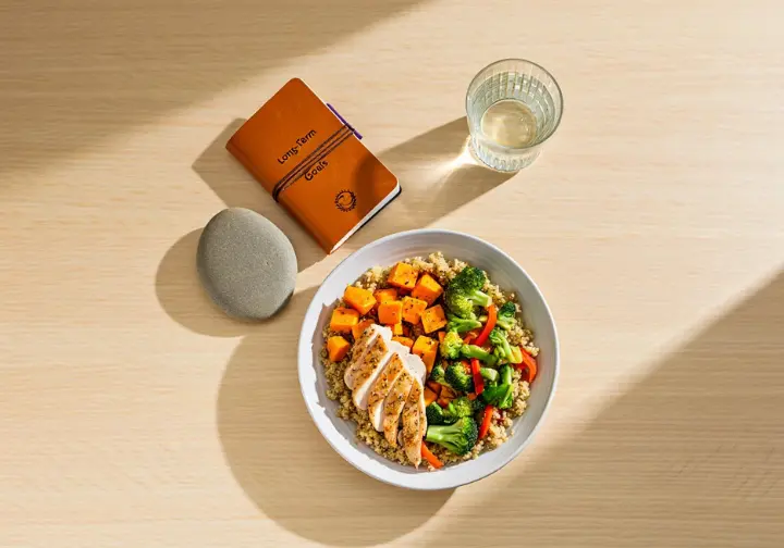 Flat lay representing a holistic approach to climbing grip strength: healthy food, water, and a journal for long-term gains.