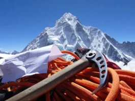Revealing the cost to climb Everest: View of Mount Everest peak with climbing gear and a budget sheet in the foreground highlighting hidden fees.
