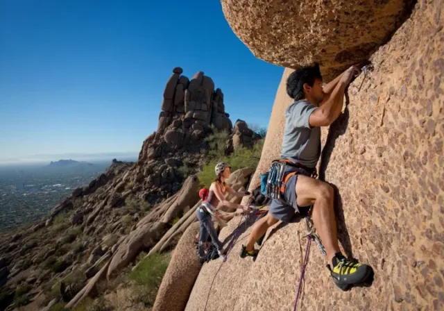 Mastering climbing the Praying Monk on Camelback Mountain: diverse climbers on a classic route with Phoenix in the background.