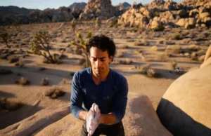 Master Joshua Tree Bouldering: Your Definitive Guide Male climber intently studying a large granite boulder in Joshua Tree National Park at golden hour, representing a definitive guide to joshua tree bouldering.
