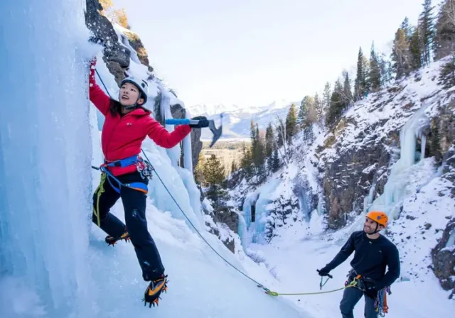 Mastering Lake City ice climbing: diverse climbers on a tall blue ice formation in the park, showcasing routes and the promise of secrets.