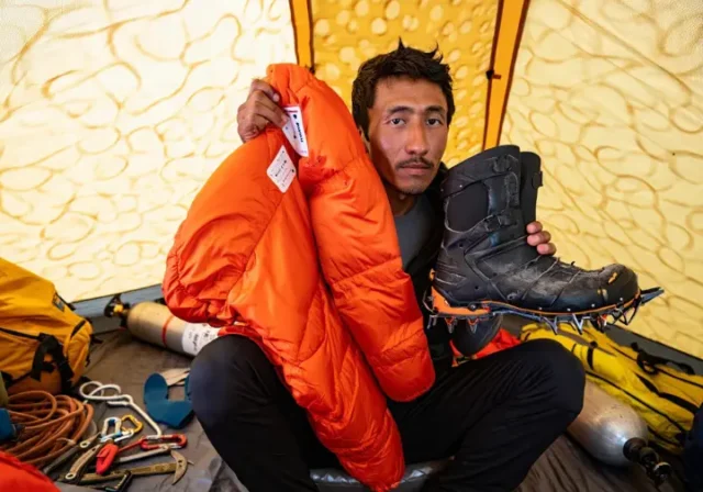 Climber contemplating the Mount Everest climbing gear rent vs buy decision inside a base camp tent.