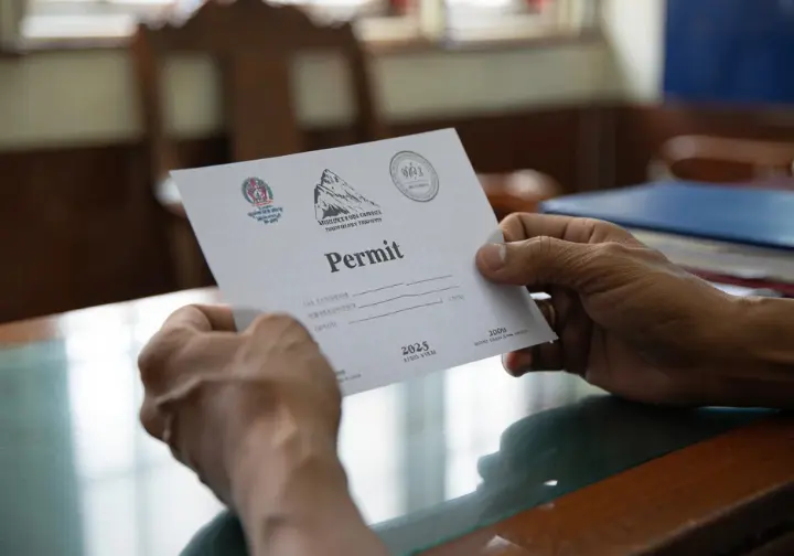 Official mandates for climbing Everest: hands reviewing a climbing permit, navigating the regulatory landscape prerequisites.