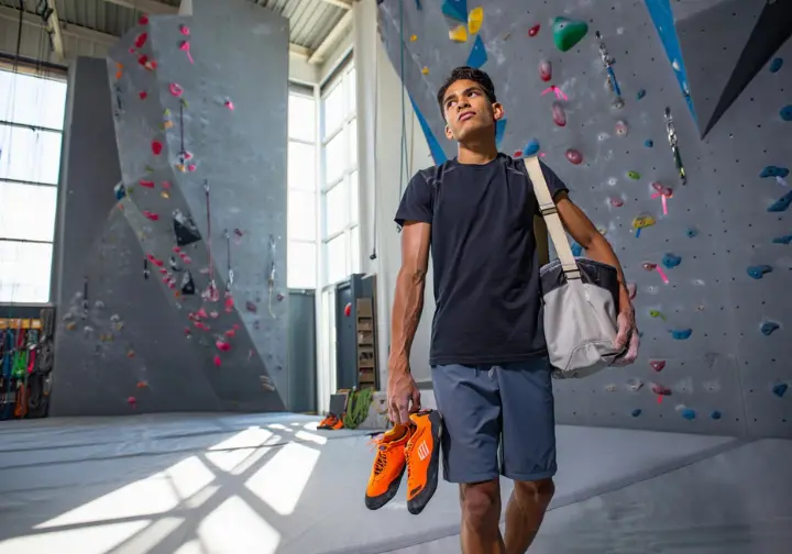 Understanding climbing needs: Person contemplating between bouldering and rope climbing sections in a San Francisco gym.
