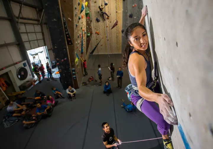 Deep dive review of Berkeley Ironworks rock climbing gym: diverse female climber lead climbing on a tall wall.