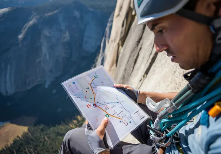 Climber on El Capitan studying a detailed Freerider topo map, for a pitch-by-pitch deconstruction of the route.