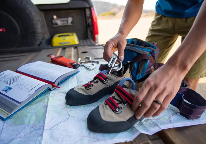 Essential San Luis Obispo (SLO) rock climbing logistics: hands organizing gear on a map, covering access and regulations.