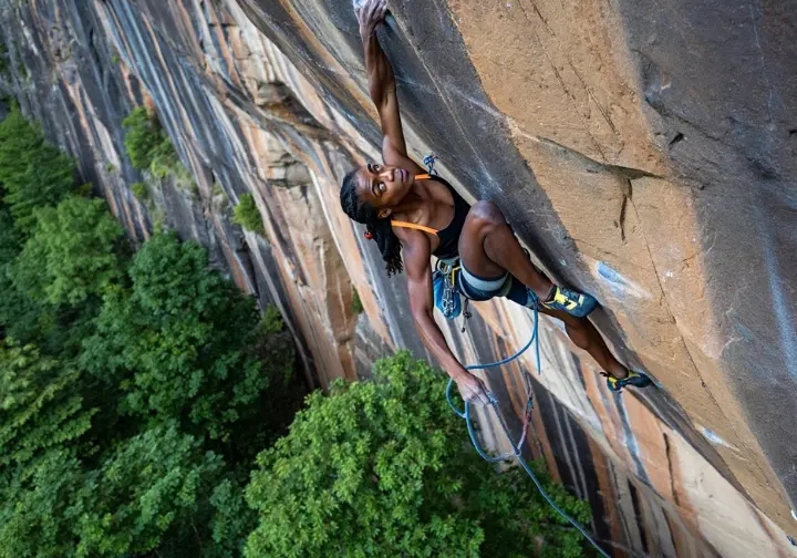 Climber executing a crux move on a classic New River Gorge route, illustrating climbing styles and beta.