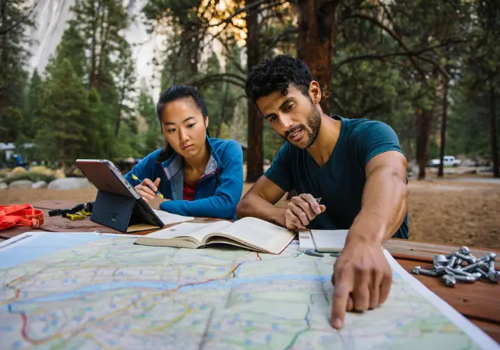 Two diverse climbers planning the Freerider ascent at a Yosemite campsite, focusing on strategy, logistics, and preparation.