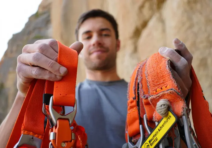 Rent versus buy decision: Climber comparing a new versus a rented piece of essential mountain climbing gear.