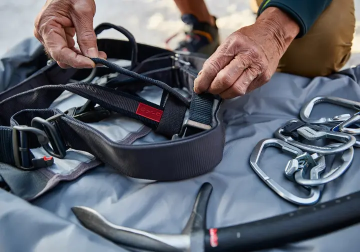 Expert advice and final checks: Climber performing a meticulous pre-expedition inspection of their climbing harness for Everest.