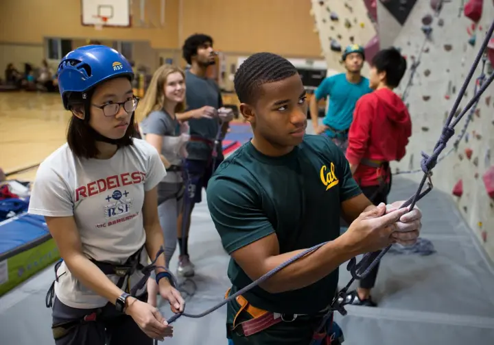 Insights into the UC Berkeley RSF rock climbing gym wall: diverse students climbing and belaying in the university facility.