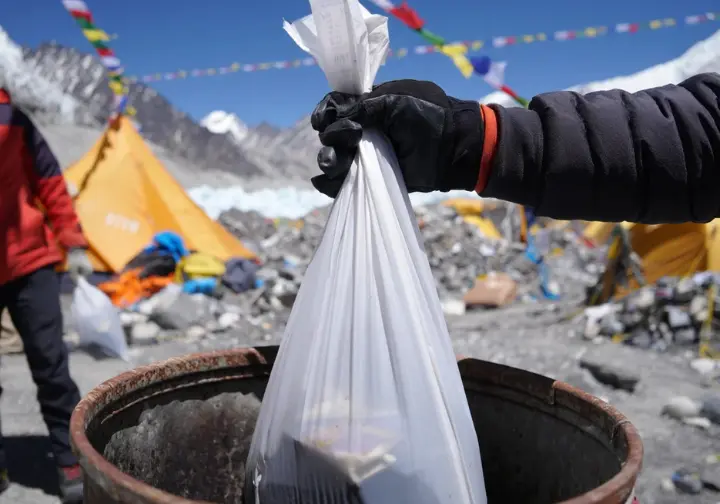 Ethical climbing on Everest: hand disposing of a WAG bag, highlighting environmental responsibility as a prerequisite