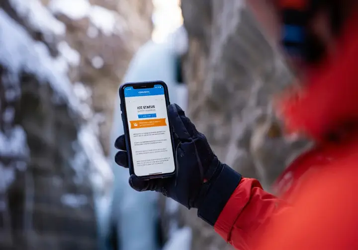 Staying safe and informed at Ouray Ice Park: Climber checking official online park conditions report on a device.
