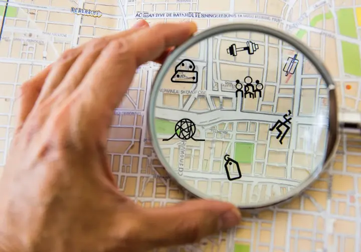 Making your choice: key factors for a Berkeley rock climbing gym, shown by a hand with a magnifying glass over a map with decision icons.