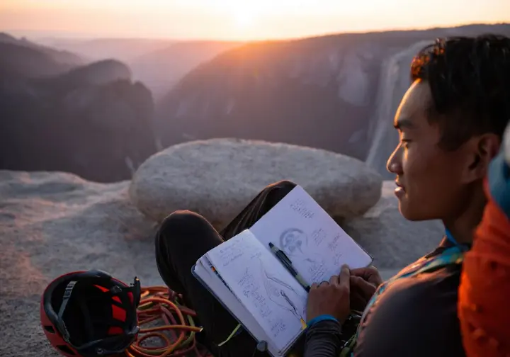 Climber reflecting with a journal on the summit of El Capitan at sunset, symbolizing the Freerider journey as a developmental framework.