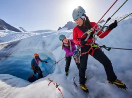 Alpinist team performing a crevasse rescue practice on a heavily crevassed glacier, using ropes, ice axes, and a hauling system, highlighting critical glacier travel and rescue skills.