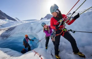 Critical Glacier Travel & Crevasse Rescue Skills Alpinist team performing a crevasse rescue practice on a heavily crevassed glacier, using ropes, ice axes, and a hauling system, highlighting critical glacier travel and rescue skills.