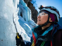 Experienced ice climber intently decoding complex ice formations and conditions on a frozen waterfall, planning safe ascent strategies with ice tools and gear.