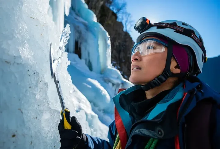 Experienced ice climber intently decoding complex ice formations and conditions on a frozen waterfall, planning safe ascent strategies with ice tools and gear.
