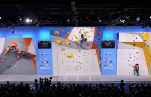 Guide to IFSC Formats: Scoring, Rules & Rounds Panoramic view of an IFSC World Cup arena showing athletes competing in Boulder, Lead, and Speed climbing, providing a guide to the formats, rules, and rounds.