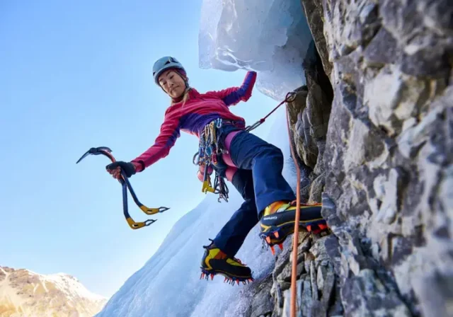 Skilled mixed climber transitioning from ice to rock, using ice tools and crampons on both surfaces, illustrating a guide to mastering mixed climbing essentials.