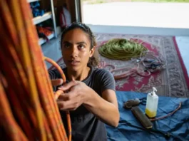 A climber embodying rope safety by inspecting a rope, with care items nearby and a retired rope repurposed as a mat, covering the full inspect, care, and retire guide.